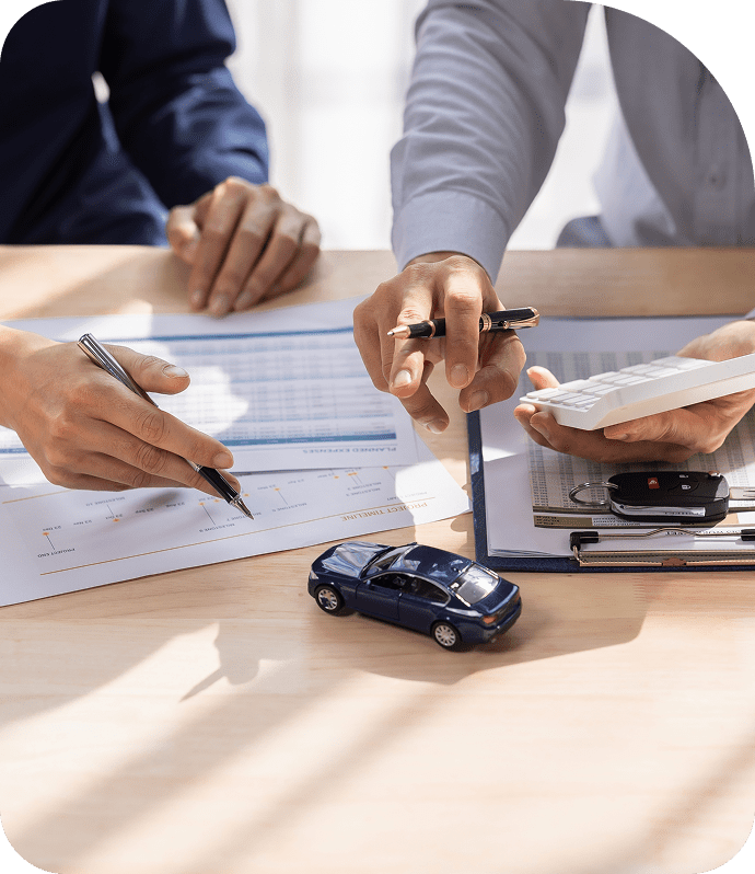 Hands discussing car documents with calculator.