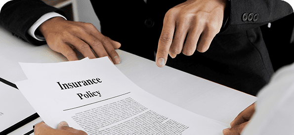 Hands pointing at an insurance policy document on a white table.